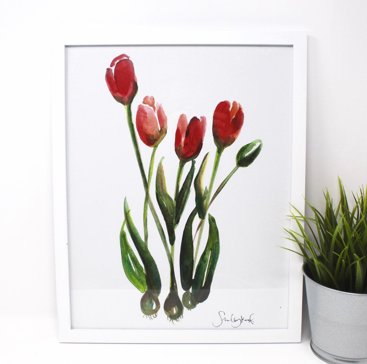 A wall art piece titled "Tulips Art Print," measuring 11x14, features a tulip painting with vibrant red tulips and lush green stems and leaves on a crisp white background, perfect for home decor.