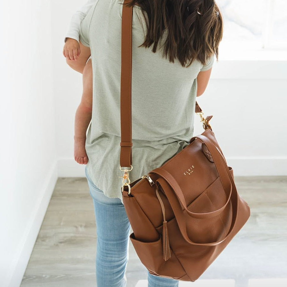 A neat row of four coiled Bag Straps featuring microfiber leather craftsmanship in gray, beige, brown, and black with adjustable gold buckles rests elegantly on a white background. These stylish Elkies accessories add the perfect touch of sophistication to any purse.