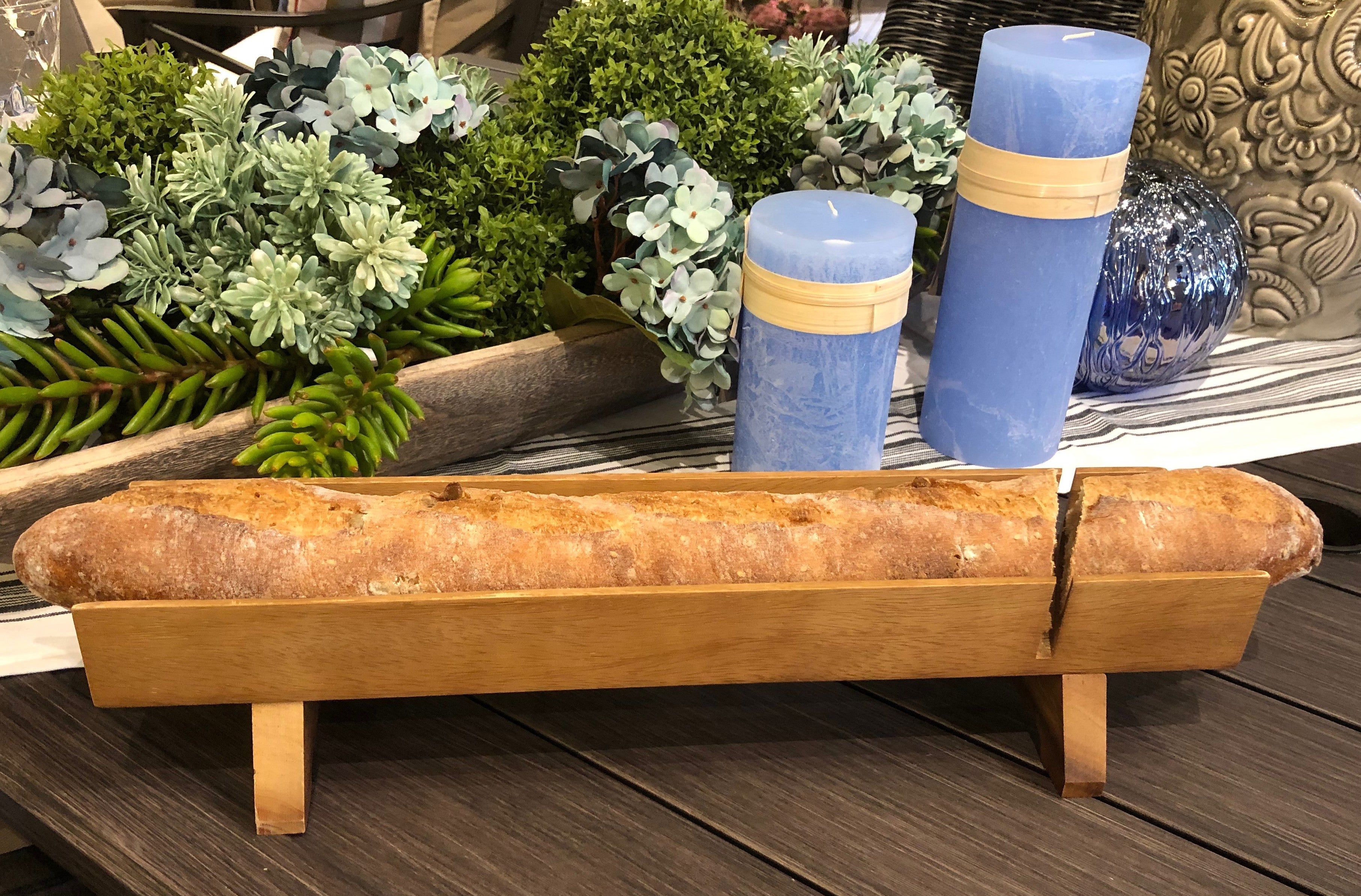 A loaf of bread is displayed on a Kronberg French Bread Slicer made of acacia wood.