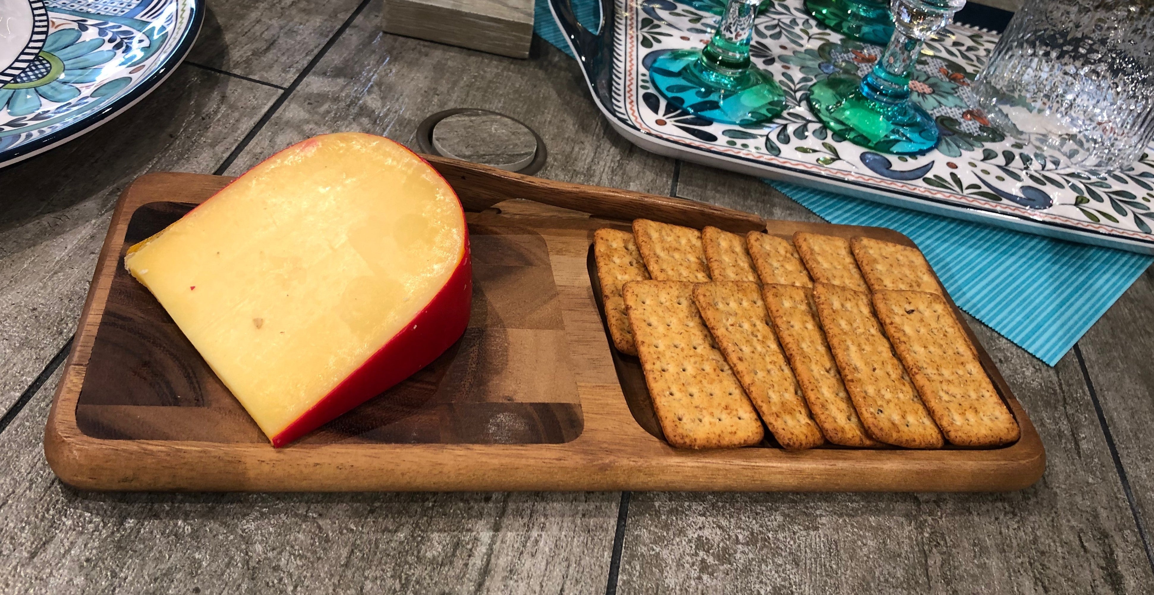 The Bornholm Cheeseboard with Knife, made from acacia wood, showcases a geometric pattern on the left and a recessed area on the right, making it an elegant choice for serving cheese.