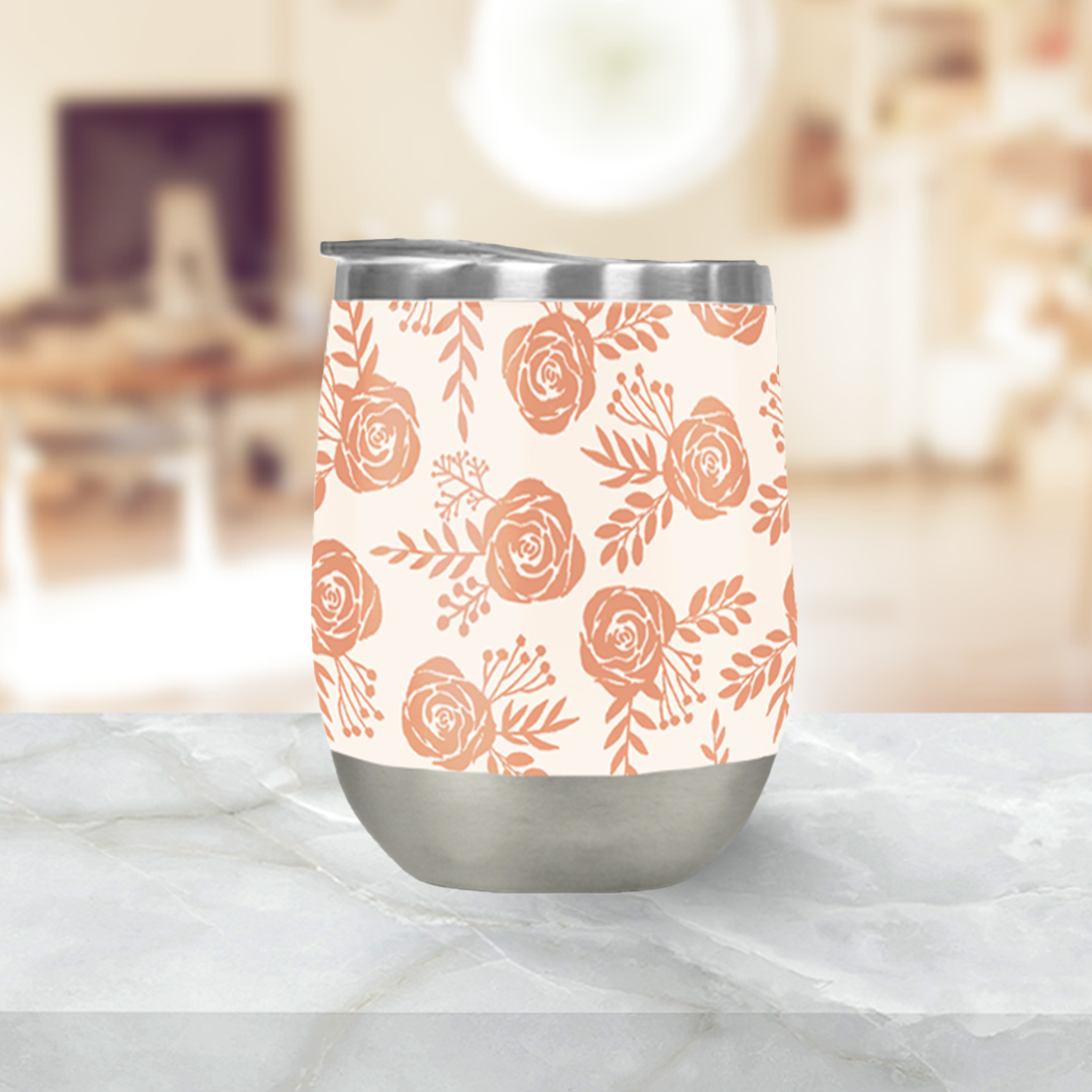 A Warm Orange Floral Wine Tumbler rests on a marble surface. Its double-wall insulation ensures your drink stays at the perfect temperature, with a blurred indoor setting in the background.