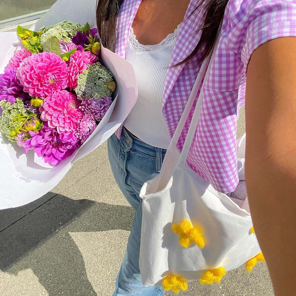 The Lily Canvas Shopper Tote is an eco-friendly cotton canvas bag featuring exquisite purple flower embroidery on the front.