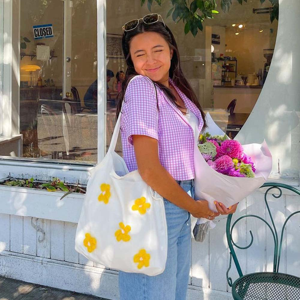 The Lily Canvas Shopper Tote is an eco-friendly cotton canvas bag featuring exquisite purple flower embroidery on the front.