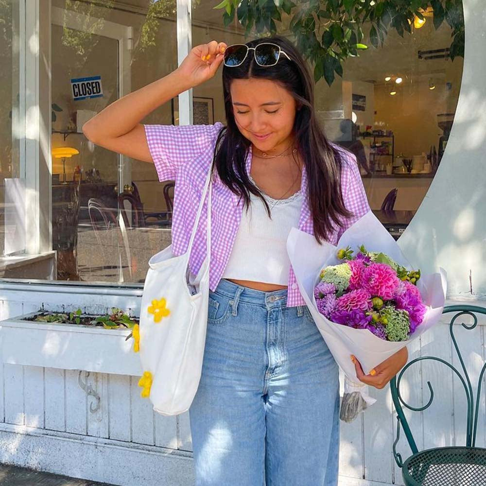 The Lily Canvas Shopper Tote is an eco-friendly cotton canvas bag featuring exquisite purple flower embroidery on the front.