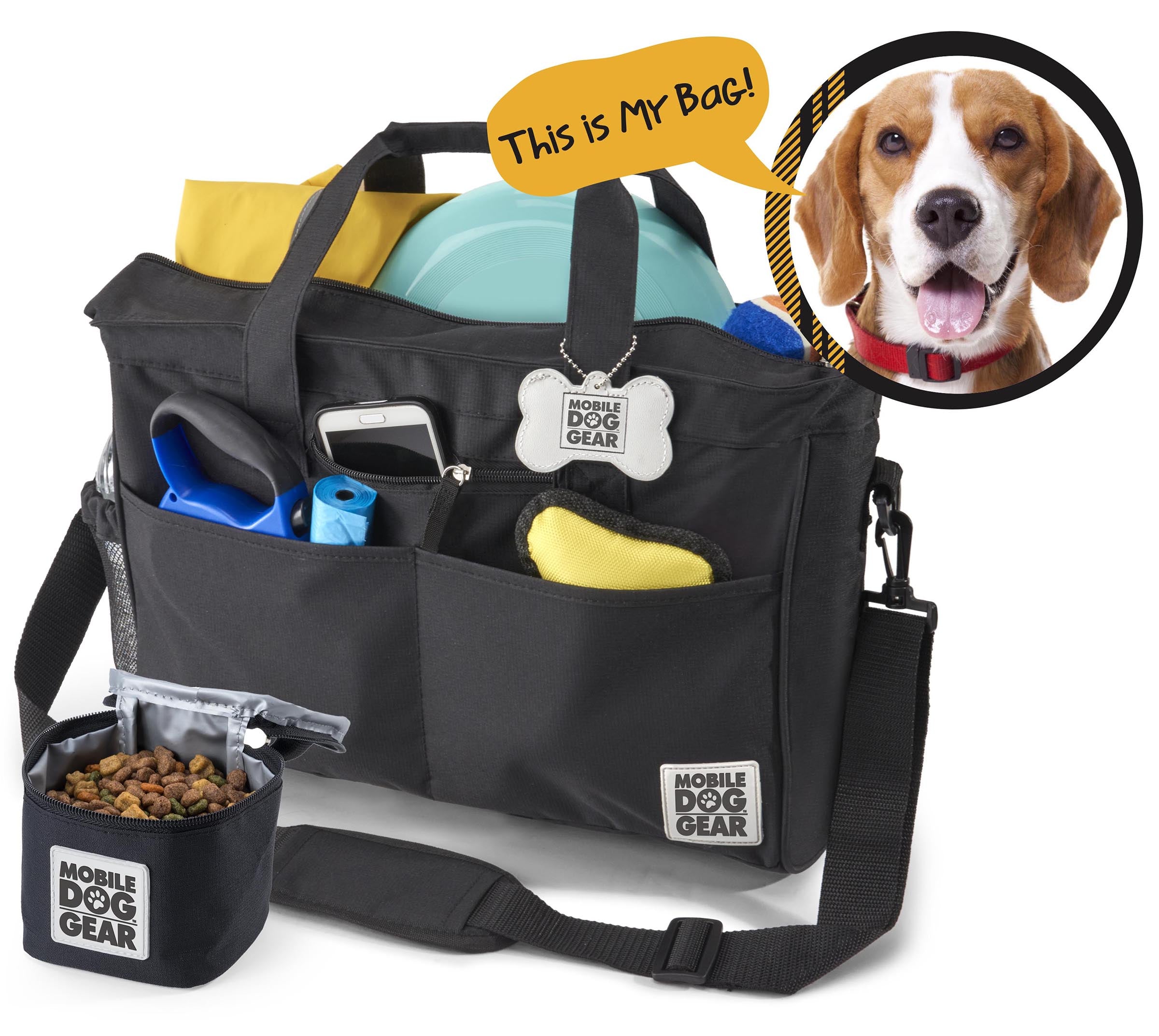 A black Day Away Tote Bag TM packed with various accessories like a phone, frisbee, and towel, accompanied by a small bag of dog food. A speech bubble from a dog image declares, "This is My Bag!" making it the perfect pet luggage for adventures.