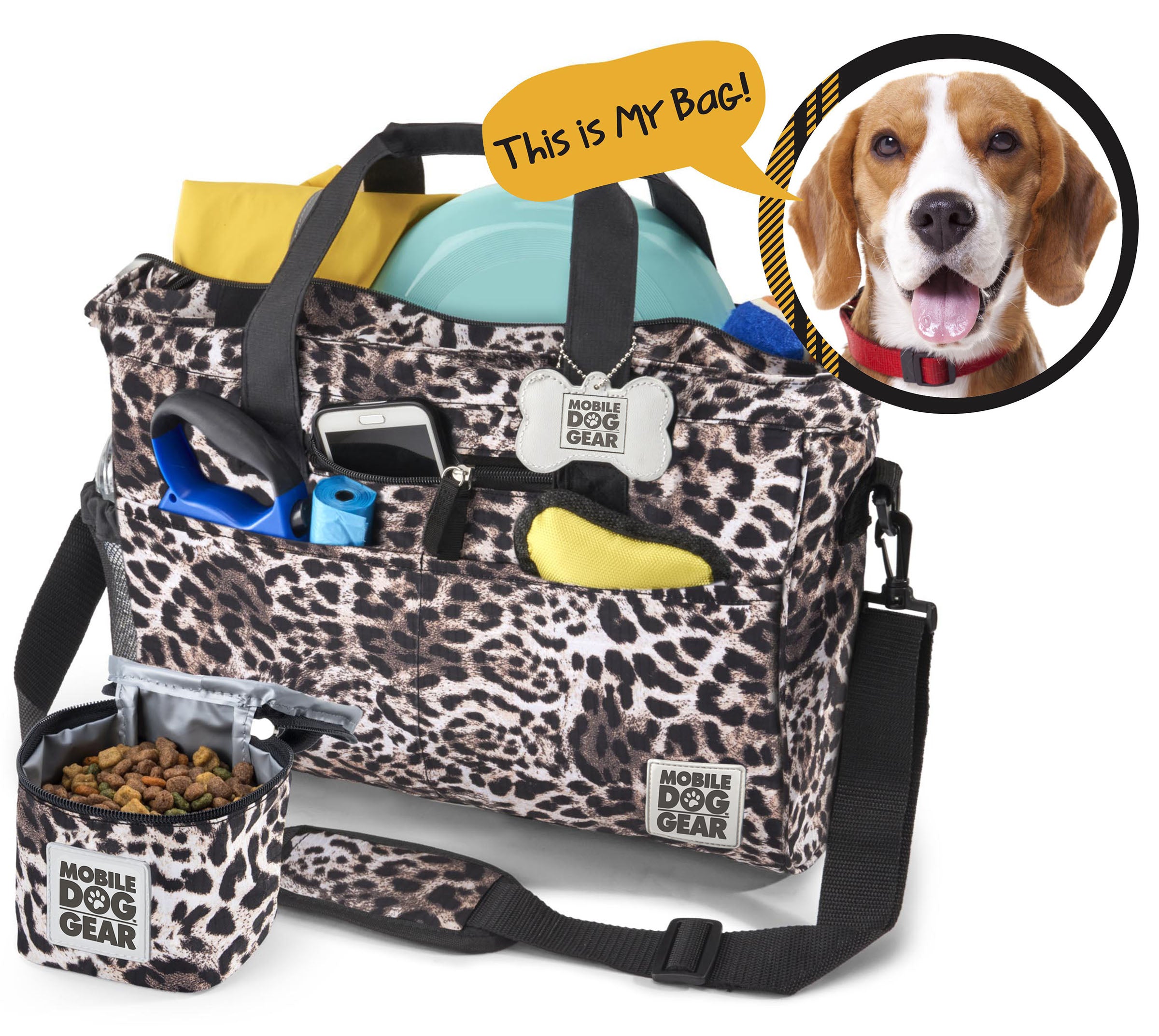 A black Day Away Tote Bag TM packed with various accessories like a phone, frisbee, and towel, accompanied by a small bag of dog food. A speech bubble from a dog image declares, "This is My Bag!" making it the perfect pet luggage for adventures.