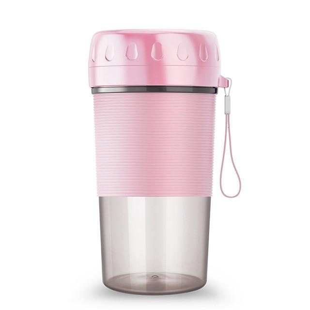 A pink and transparent Portable Personal Juice Blender and Smoothie Maker with a lid featuring a carrying strap, ribbed grip section, and translucent bottom half doubles as a personal wireless juice blender rechargeable via USB.