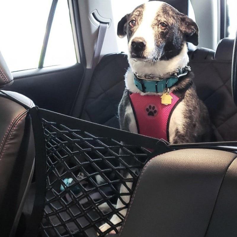 A shiba inu dog standing in a car, peeking through a black High Quality Premium Pet Car Net Petition barrier installed between two front seats.