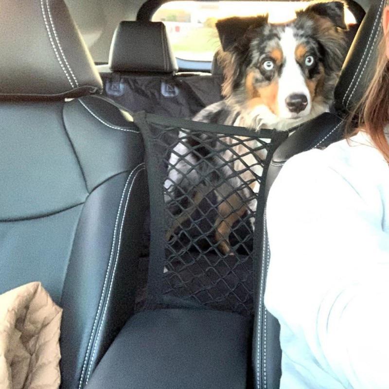 A shiba inu dog standing in a car, peeking through a black High Quality Premium Pet Car Net Petition barrier installed between two front seats.