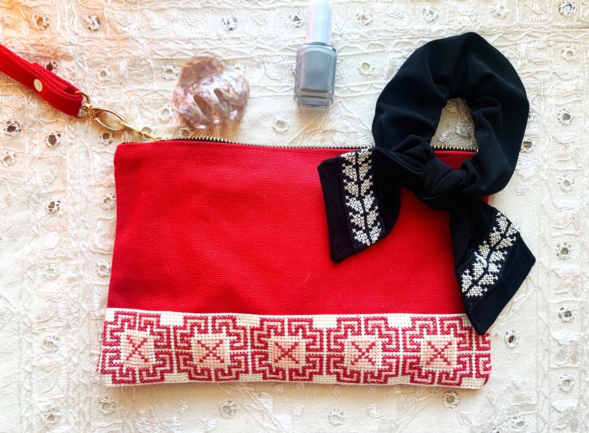 The Safa Tatreez Pouch - Red showcases exquisite Palestinian tatreez with intricate geometric patterns along the bottom edge. Hand-embroidered with care, it supports fair trade practices.