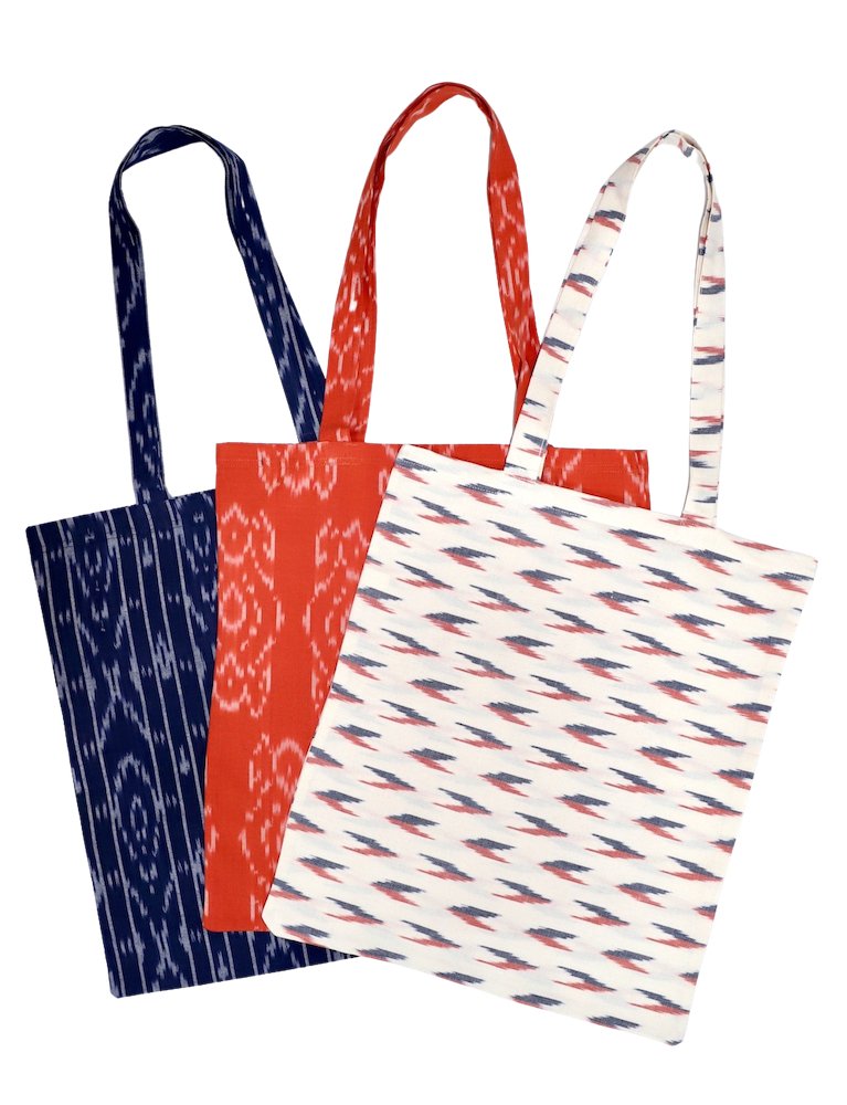 A trio of "Reusable Tote Bag: Multiple Prints Available" in ikat patterns featuring navy, red, and white are artfully displayed in a fan shape, embodying a dedication to zero waste living.