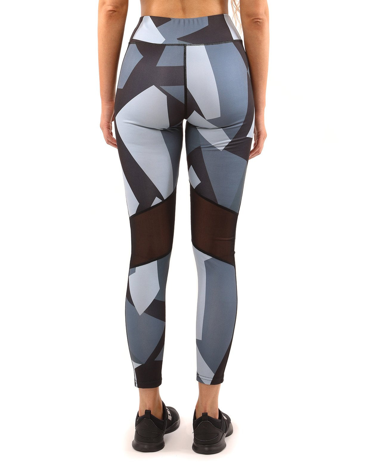 A person stands against a white background, highlighting the stylish Bondi Set in Black/Grey, featuring a geometric-patterned sports bra and compression fit leggings.
