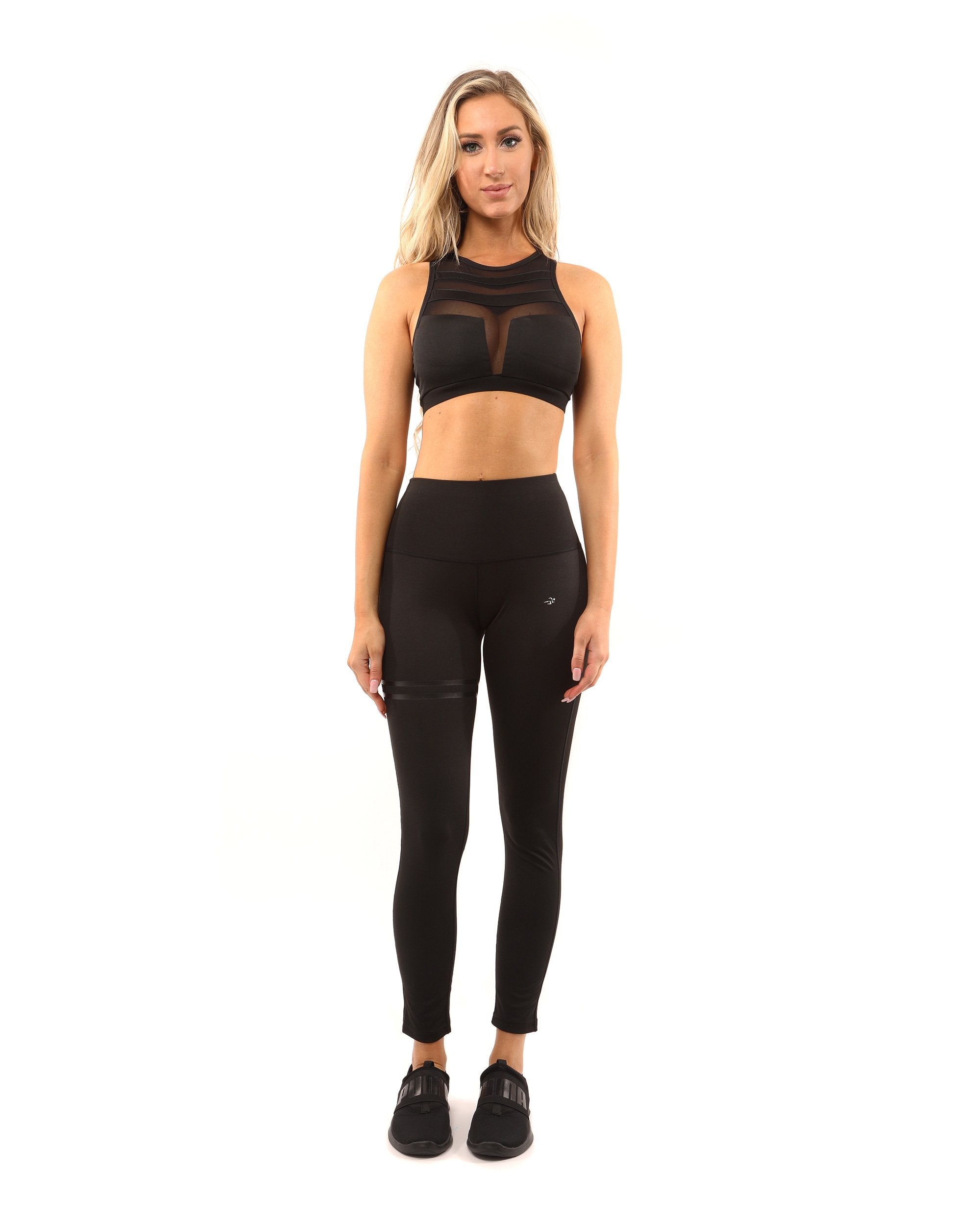 A person wearing the Laguna Sports Bra in black, featuring mesh detailing and a racerback design, stands against a white background.