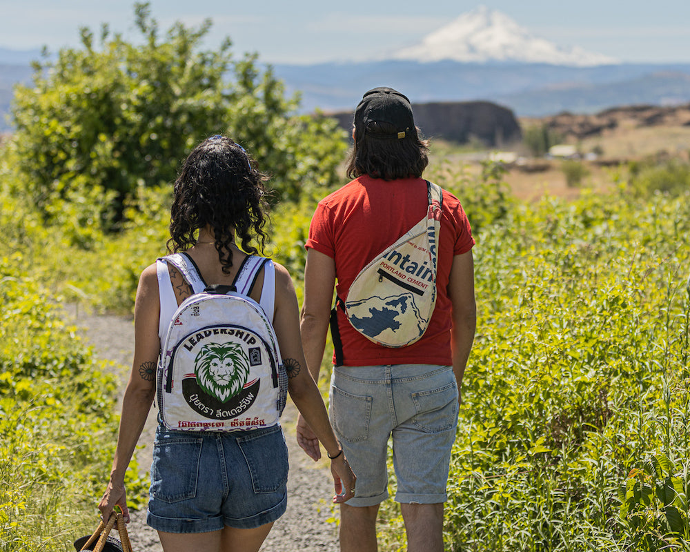 Introducing the Scout Backpack: a chic day pack that features a topographic pattern crafted from upcycled materials, with a vibrant yellow front, an orange top, and sleek black sides, all set against a pristine white background.