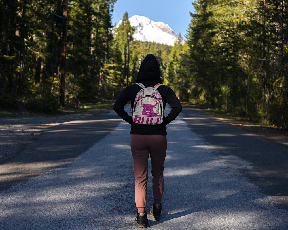 Introducing the Scout Backpack: a chic day pack that features a topographic pattern crafted from upcycled materials, with a vibrant yellow front, an orange top, and sleek black sides, all set against a pristine white background.