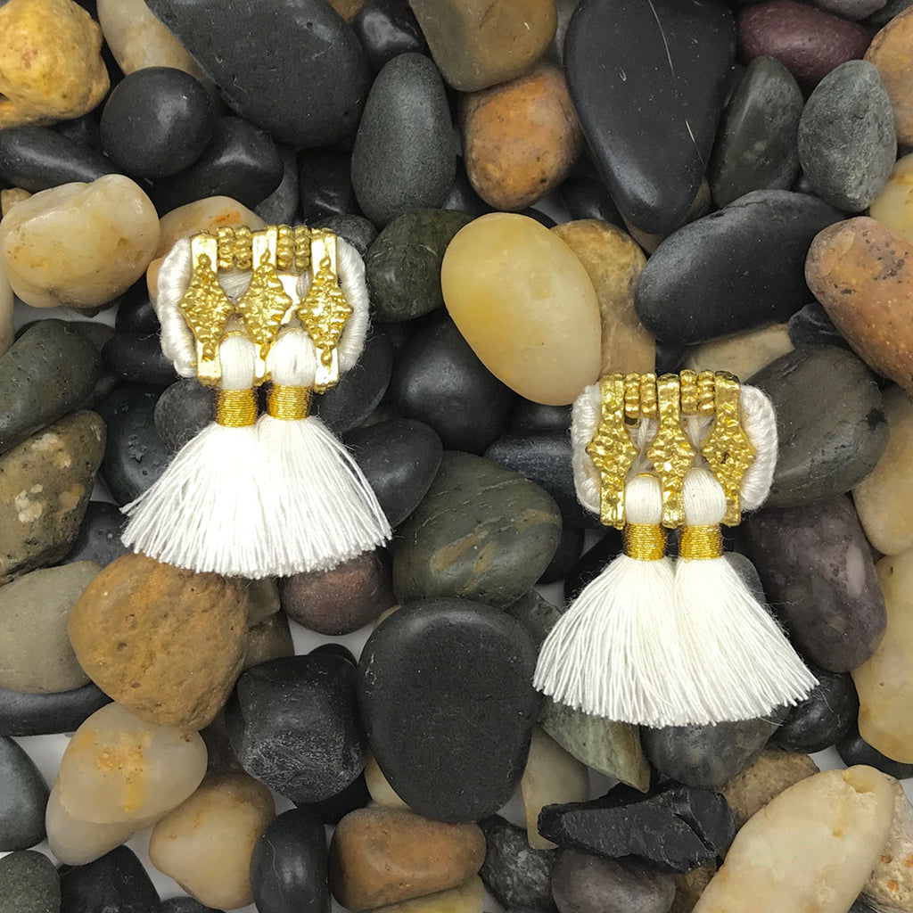 A pair of Jhumka Earrings in gold and black, showcasing detailed geometric designs with fringed ends.