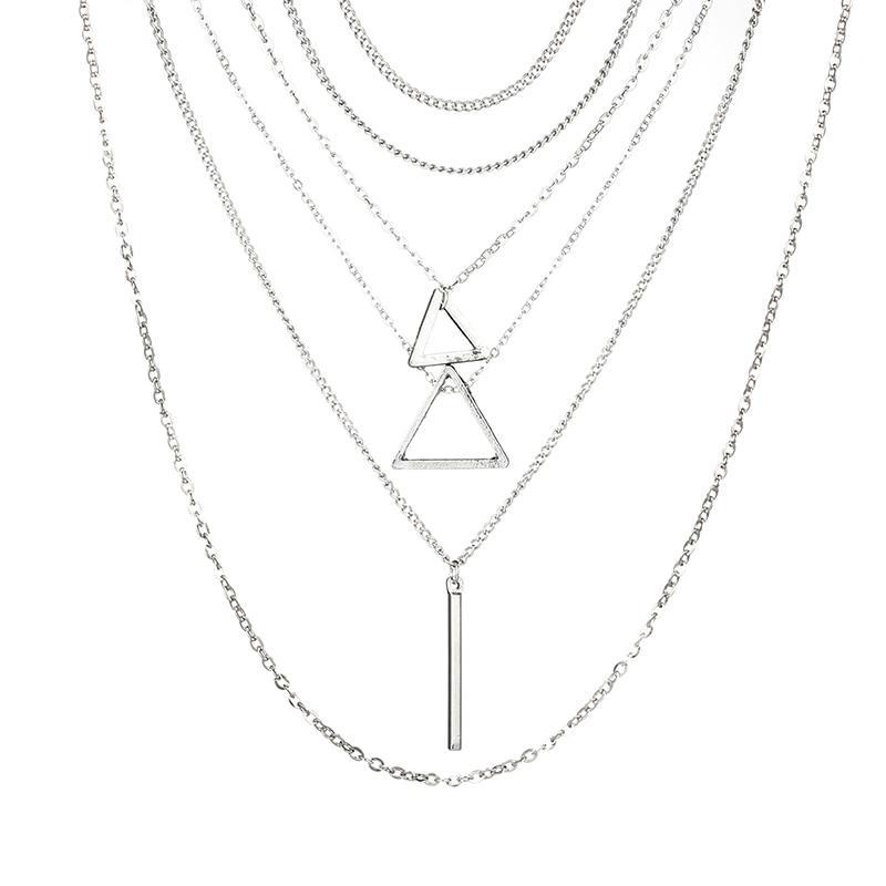 A person with long hair wears a stunning Double Triangle Multilayer Necklace, featuring zinc alloy with an adjustable chain and geometric shapes. Complementing their look is a textured sleeve and a bracelet on their wrist.