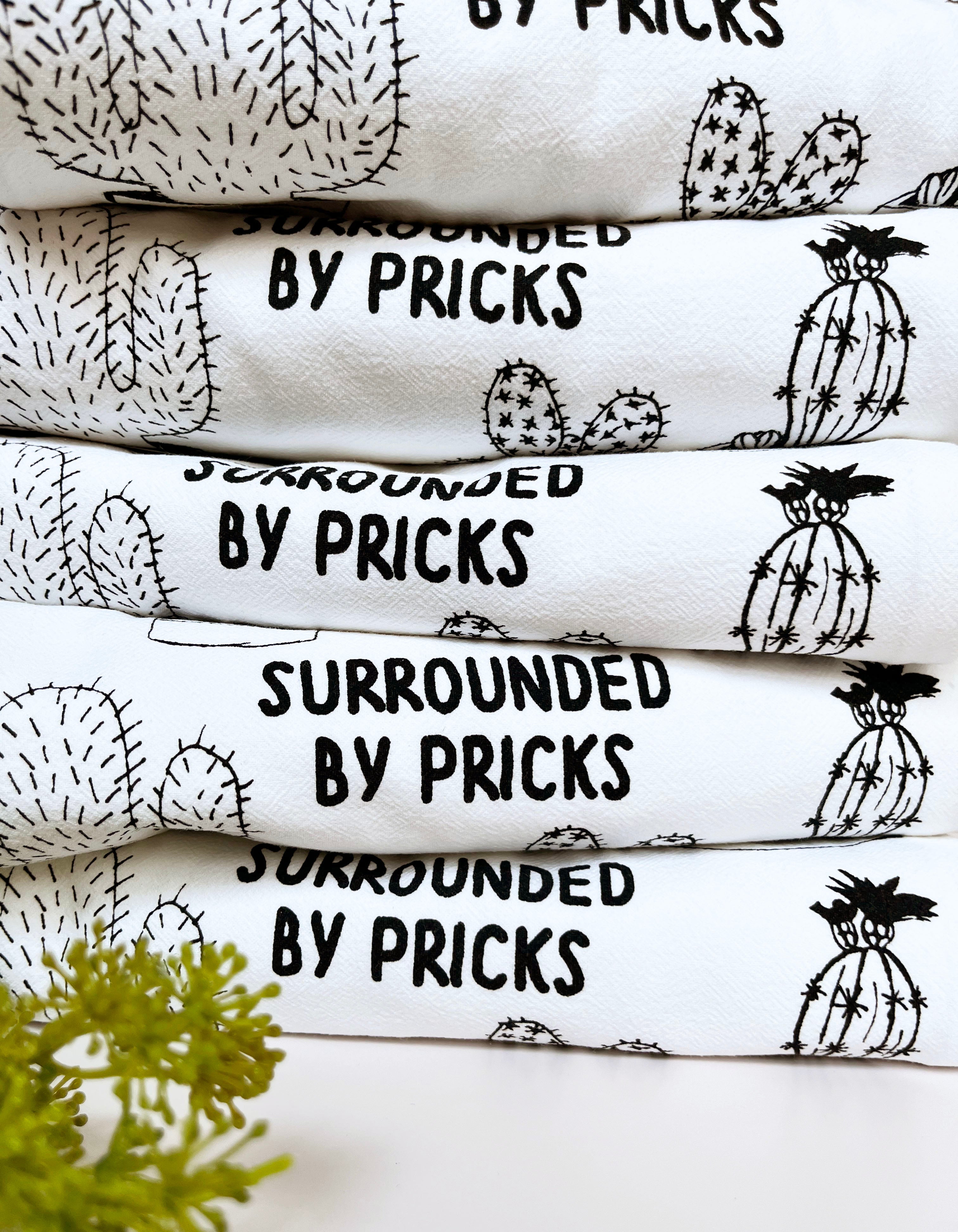 Introducing the "Surrounded by Pricks Cotton Kitchen Towel," a lint-free cotton towel featuring black line drawings of various potted cacti accompanied by the playful text "Surrounded by Pricks." Ideal for an eco-friendly kitchen, this towel makes a wonderful gift for plant enthusiasts who value humor and sustainability.