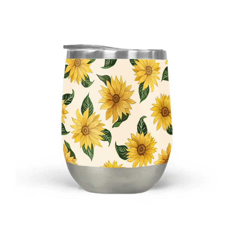 The Summer Sunflower Stemless Wine Tumbler rests on a wooden table against a blurred backdrop, showcasing its stainless steel design with a sunflower pattern and double-wall vacuum insulation. This 12 oz wine tumbler is both BPA and lead-free, guaranteeing each sip is safe as it is stylish.