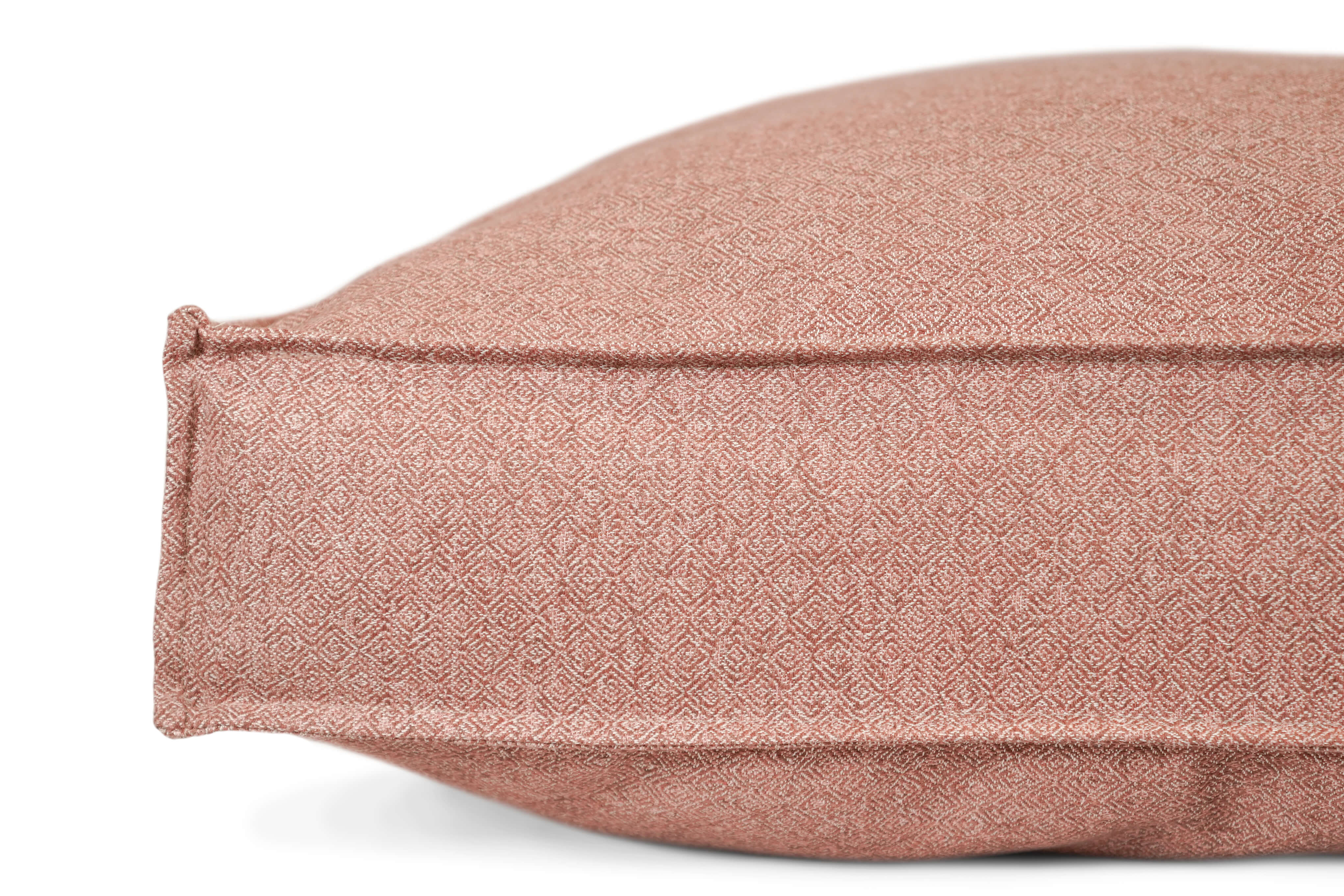 The Lounger Pet Bed in Pittie Pink features a textured surface with a repeating geometric pattern in shades of red and white, reminiscent of intricate woven or embroidered fabric, crafted from Sunbrella fabric made using recycled plastic water bottles.