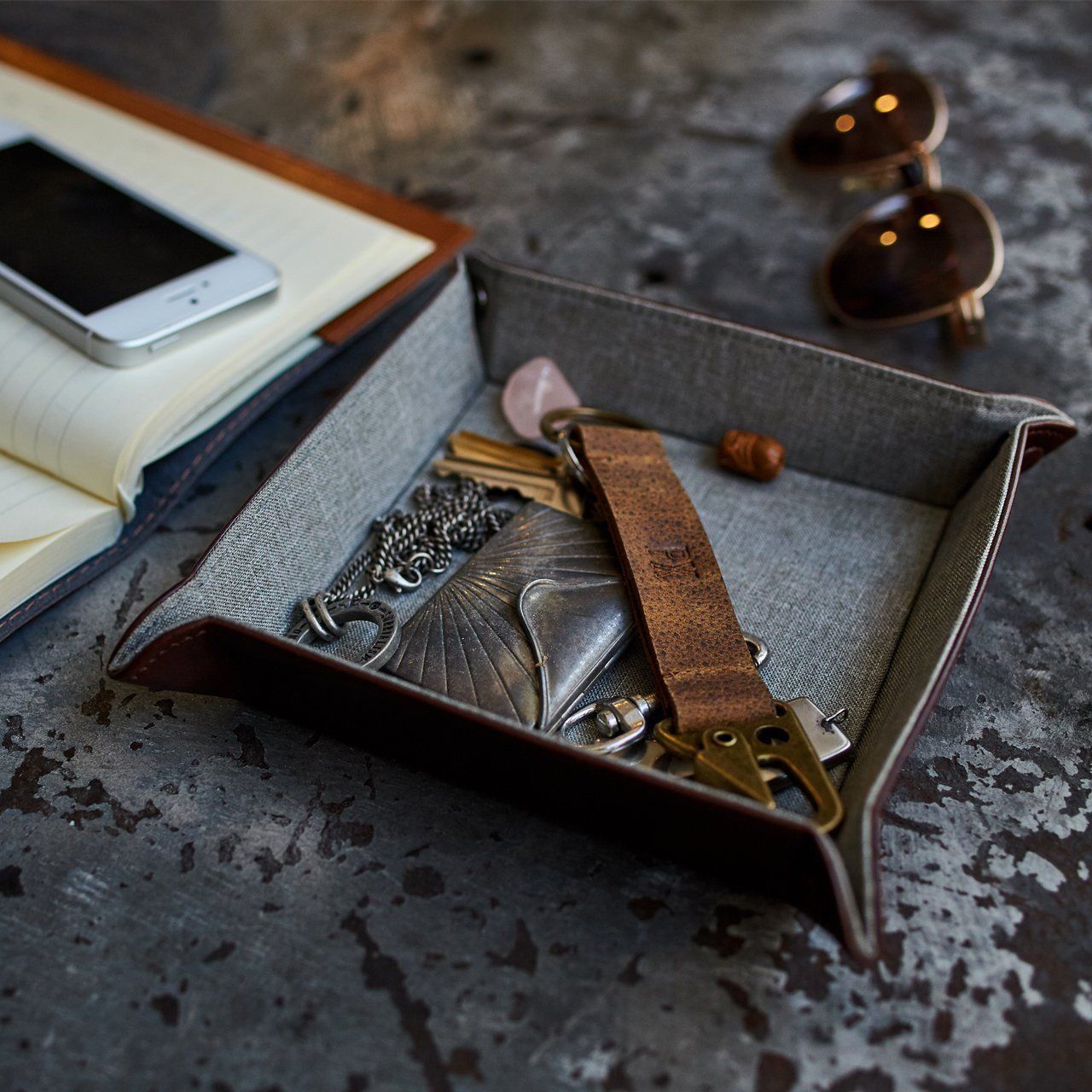 The Floyd Foldable Valet Tray is a rectangular leather organizer featuring raised sides and corner buttons, ideal for storing small items such as keys.