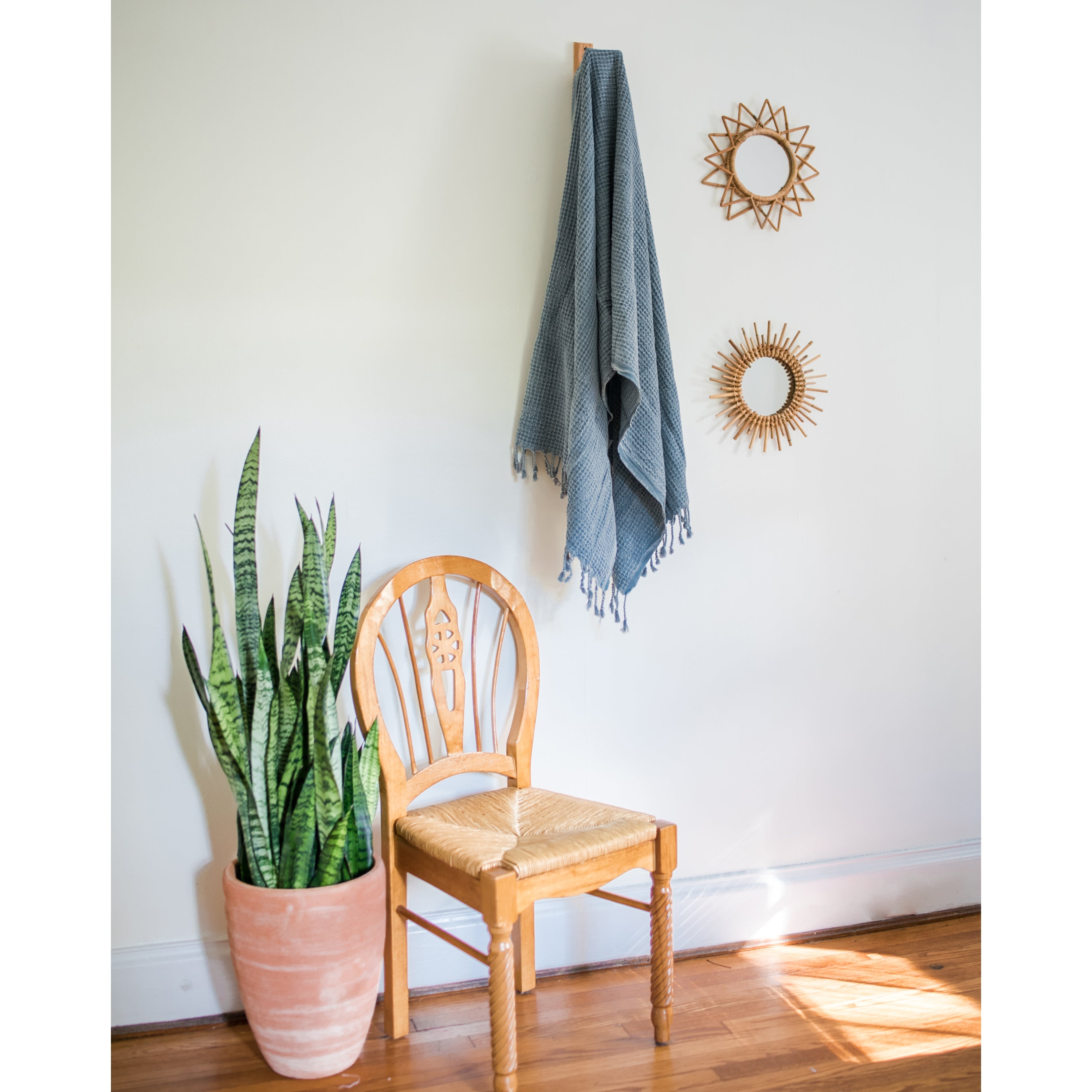 A folded, light gray blanket featuring a waffle texture and fringe tassels at the bottom mirrors the elegance of the Waffle Weave Turkish Towel, combining style and practicality for any cozy setting.