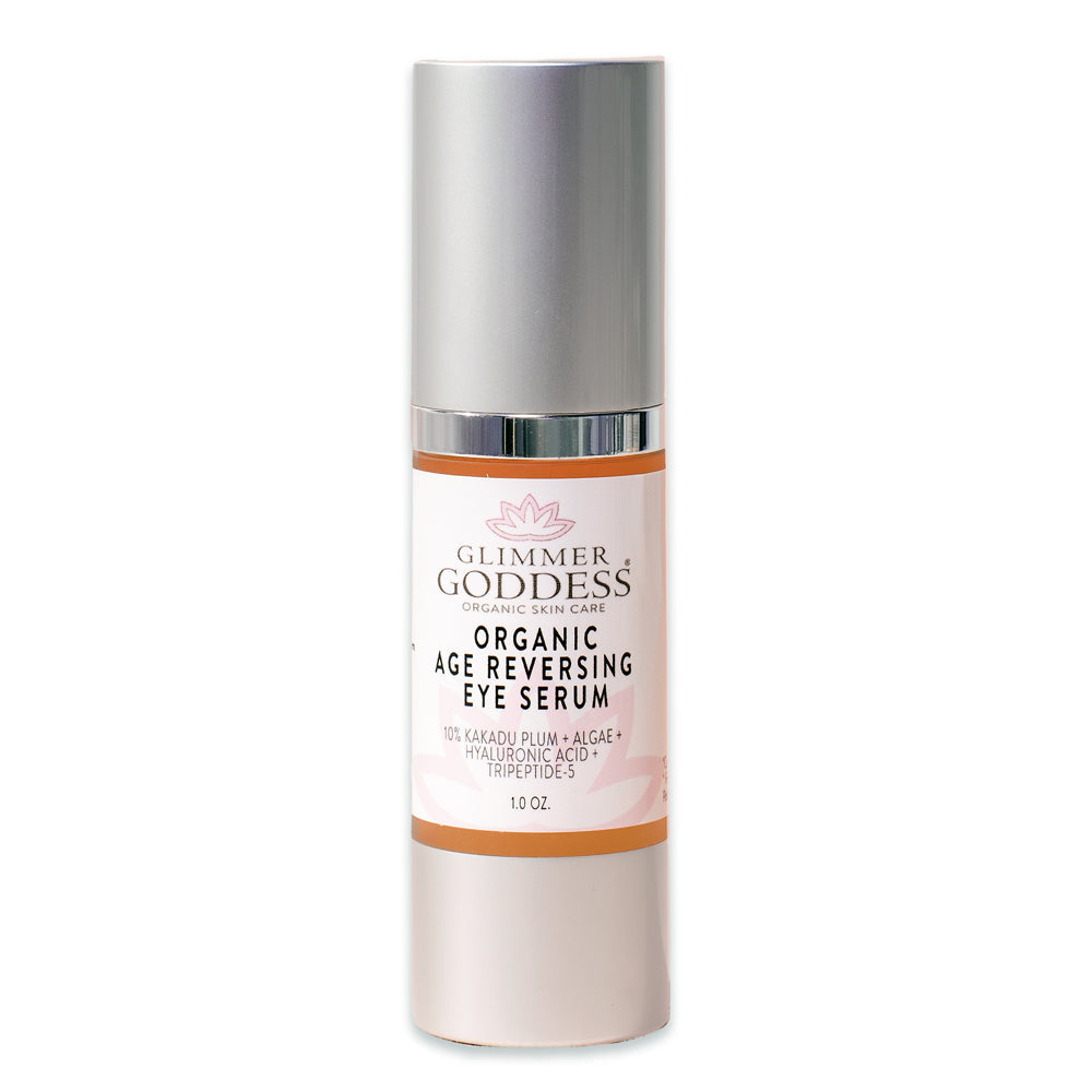 A bottle of Organic Age Reversing Eye Serum - Instantly Firms with pink and silver packaging, highlighting ingredients like Kakadu plum, hyaluronic acid, and Vitamin C.