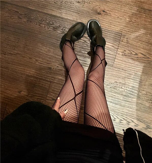 A rebellious woman wearing Edgy Elegance fishnet stockings and black boots.