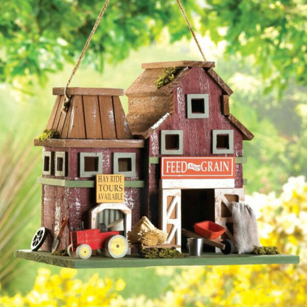 A Songbird Valley Feed and Grain Farmhouse Bird House with a red barn and a tractor.