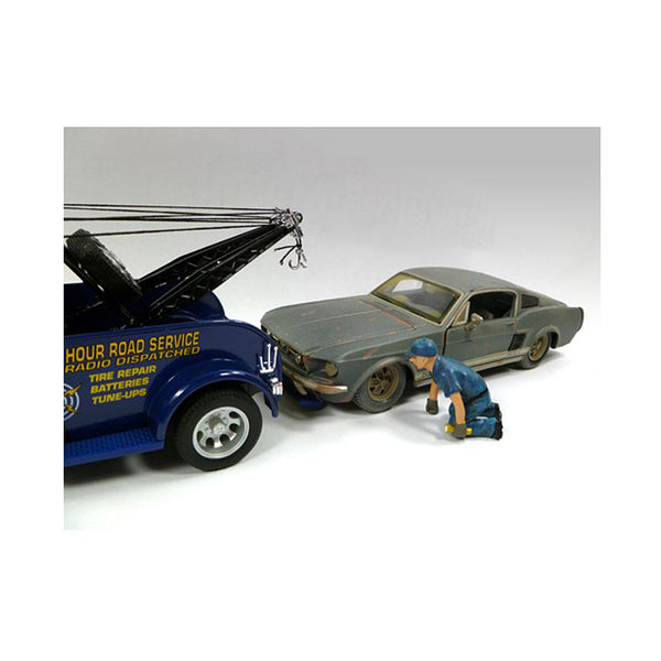 A toy car with a Tow Truck Driver/Operator Scott Figurine for 1/24 Scale Models by American Diorama next to it.