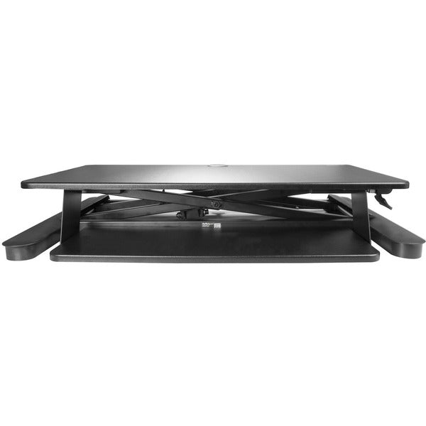 A StarTech.com Sit Stand Desk Converter - Keyboard Tray - Height Adjustable Ergonomic Desktop/Tabletop Standing Desk - Large 35"x21" Surface with a laptop on top.