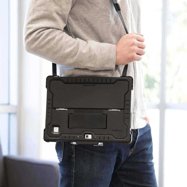 A man is holding a Targus THZ811GLZ Rugged Carrying Case HP Notebook - Black in a living room.