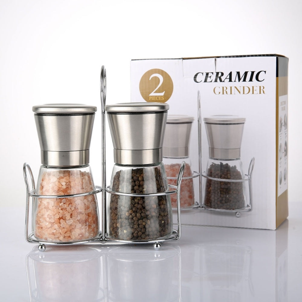 Two large capacity manual pepper mills with adjustable grind settings in a stainless steel holder, filled with pink Himalayan salt and mixed peppercorns.