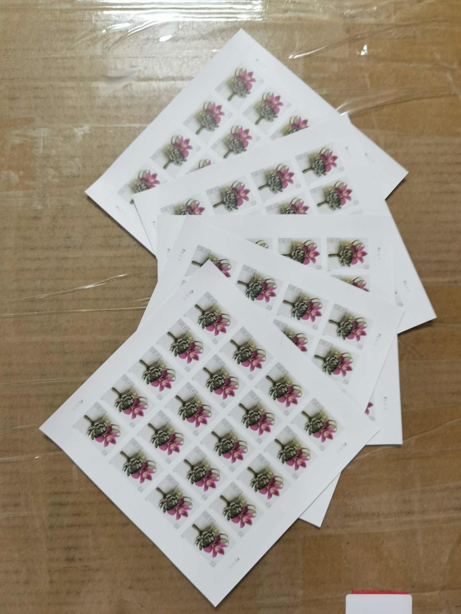 A sheet of First-Class Rate 2020 U.S. STAMPS featuring a contemporary boutonniere design, placed on a cardboard surface.