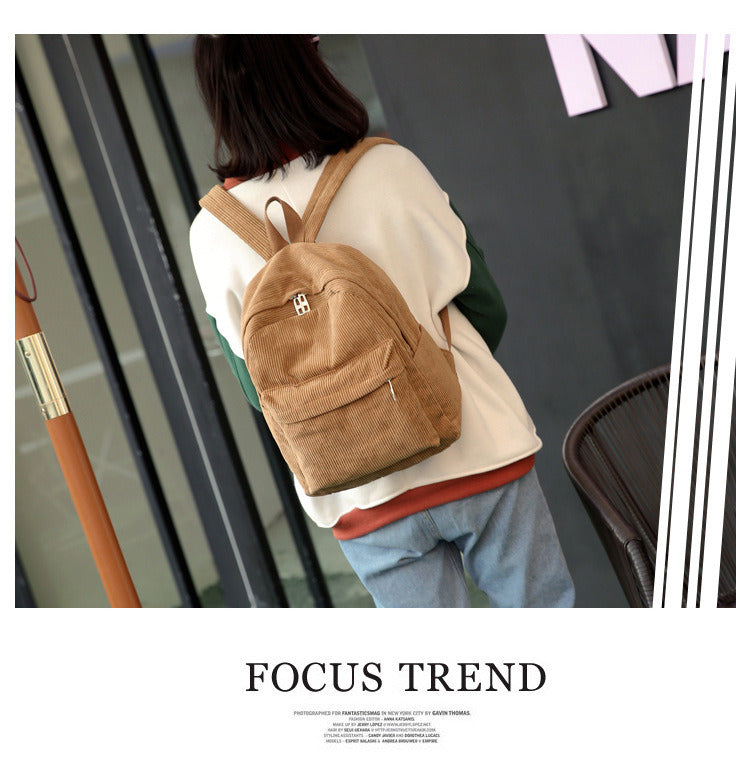 A Corduroy Backpack Fashion Women Bookbags Pure Color Shoulder Bag Teenger Girl Travel Bag Mochila Striped Rucksack sitting on top of a table.