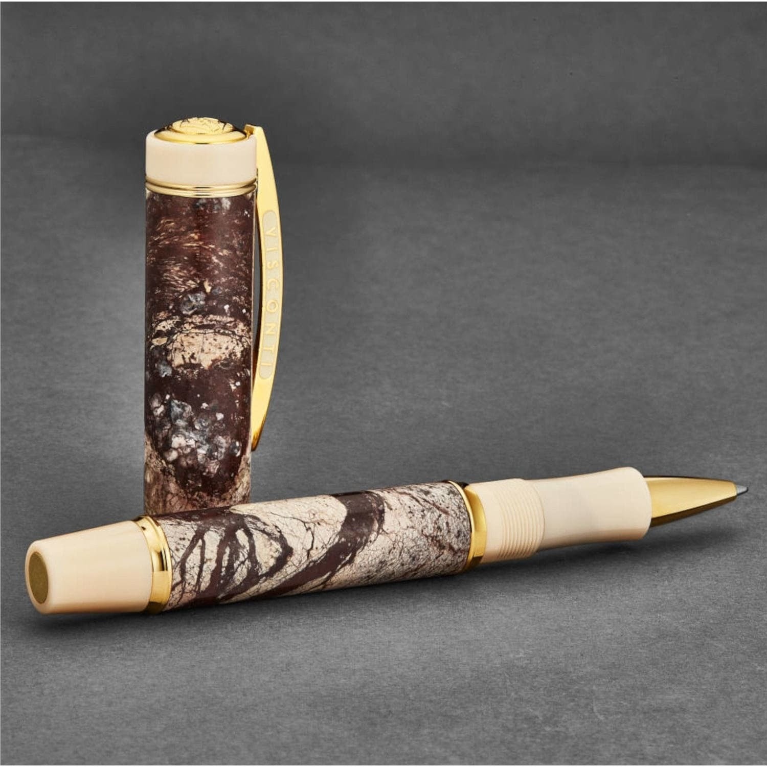 A Visconti 685RL02 'Millionaire' Rain Forest Brown Marble rollerball pen with a camouflage pattern and gold trim.