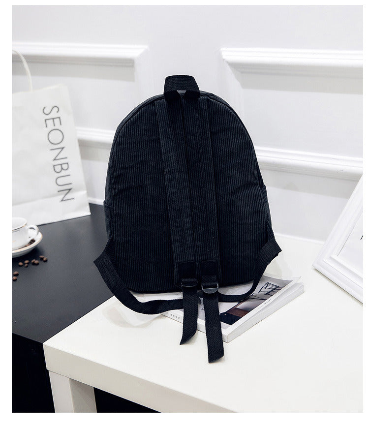 A Corduroy Backpack Fashion Women Bookbags Pure Color Shoulder Bag Teenger Girl Travel Bag Mochila Striped Rucksack sitting on top of a table.