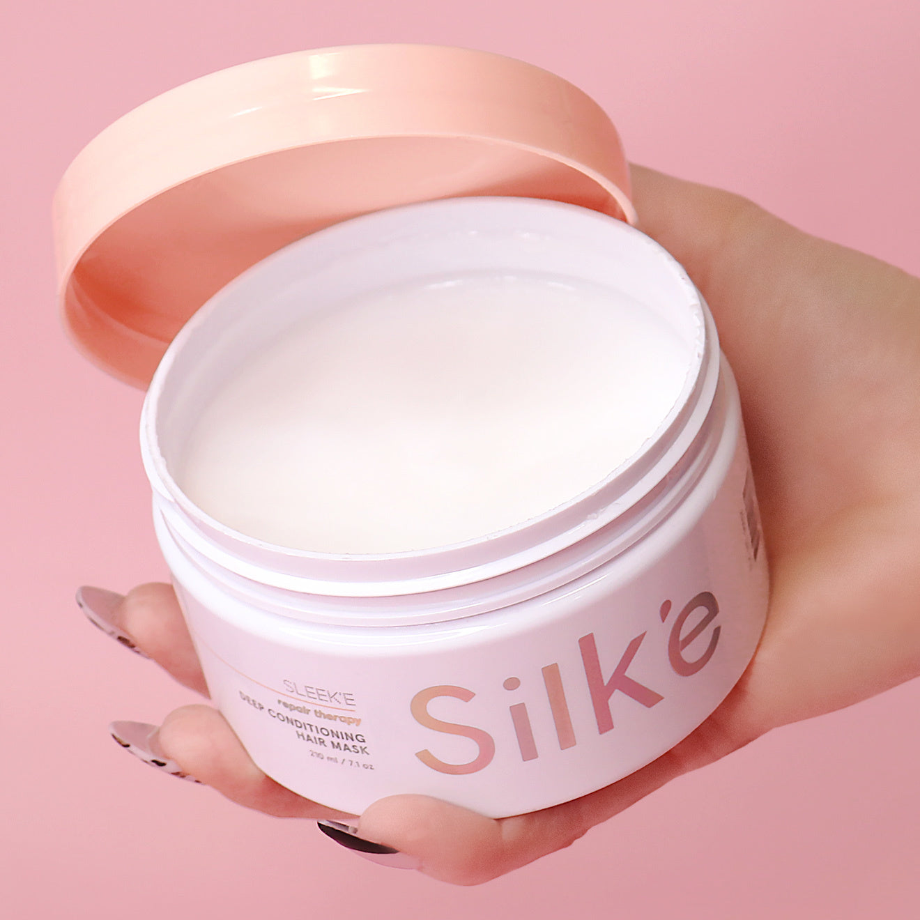 A jar of Silk'e Repair therapy Hair Mask on a pink background.