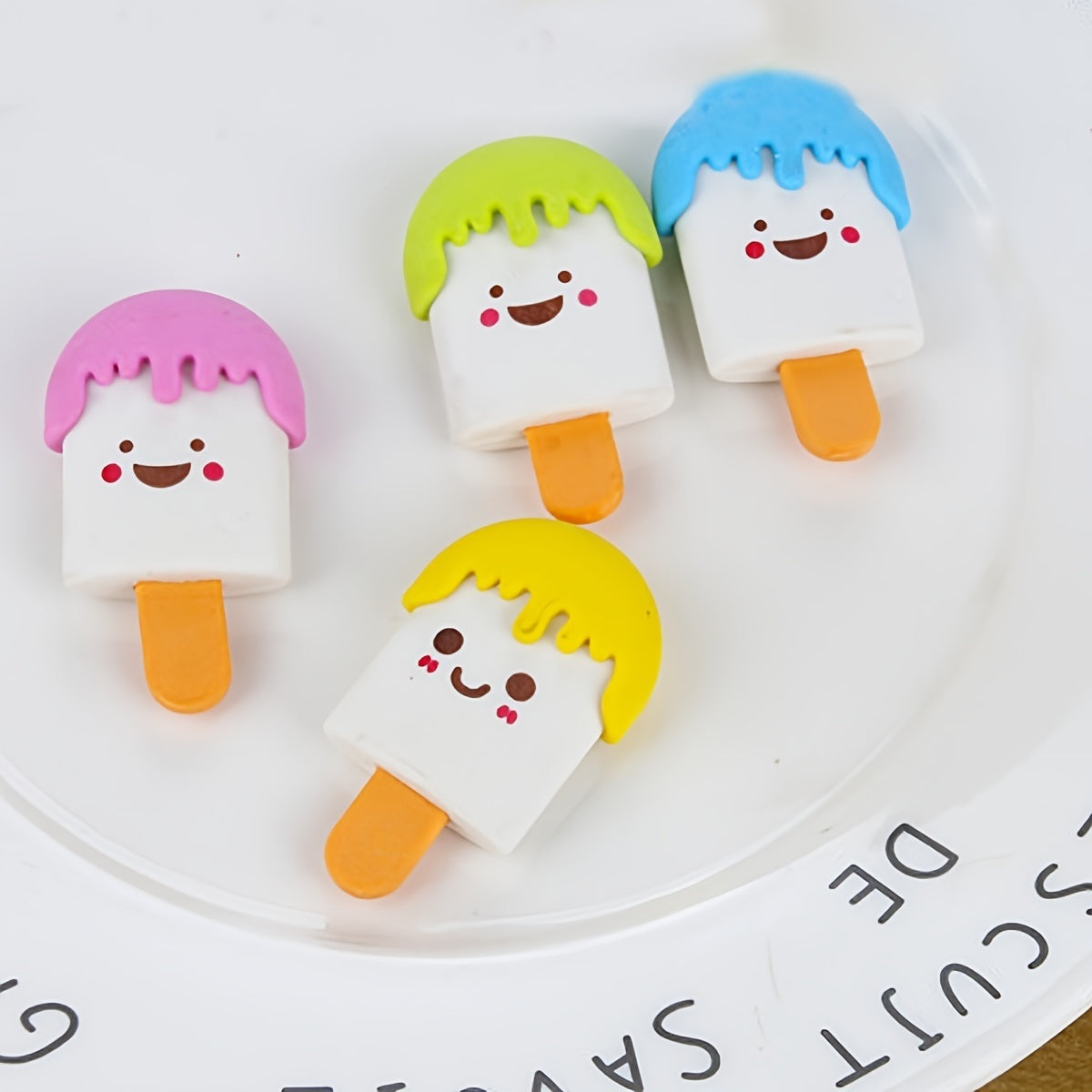 Four colorful 4pcs Ice Cream Shaped Erasers with cartoon faces, displayed on a bench against a backdrop labeled "Chanel.