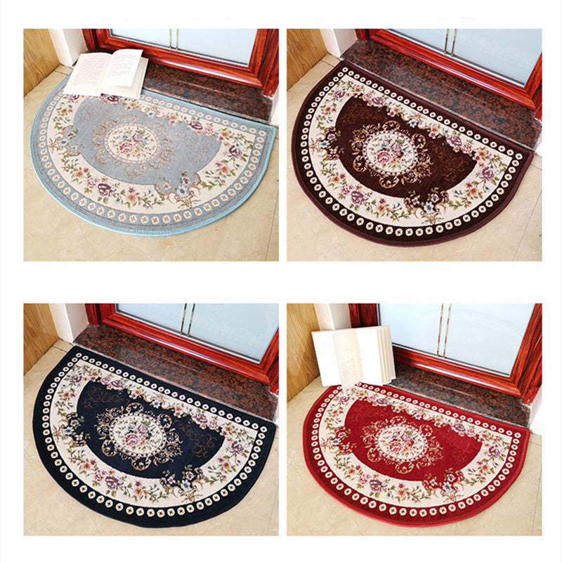 A European Style Semicircle Entrance Carpet with floral designs and a pastel color scheme on a wooden floor, next to a stool and a pair of slippers.