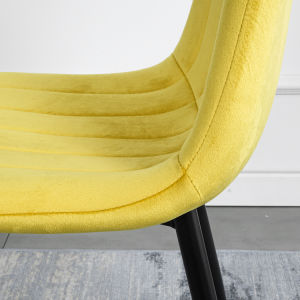 A modern dining room with a white table, four Indoor Velvet Dining Chairs with velvet fabric, and a gray rug, against a blue and white wall with minimalistic artwork.
