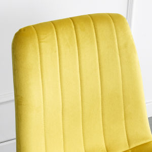 A modern dining room with a white table, four Indoor Velvet Dining Chairs with velvet fabric, and a gray rug, against a blue and white wall with minimalistic artwork.