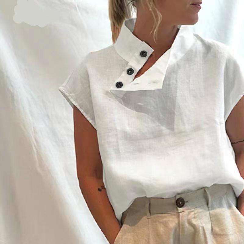 Person wearing a Stylish Blouses Summer Women Cotton Linen Short Sleeve Buttons Solid Shirt in navy blue, paired with light-colored trousers, standing against a plain backdrop.