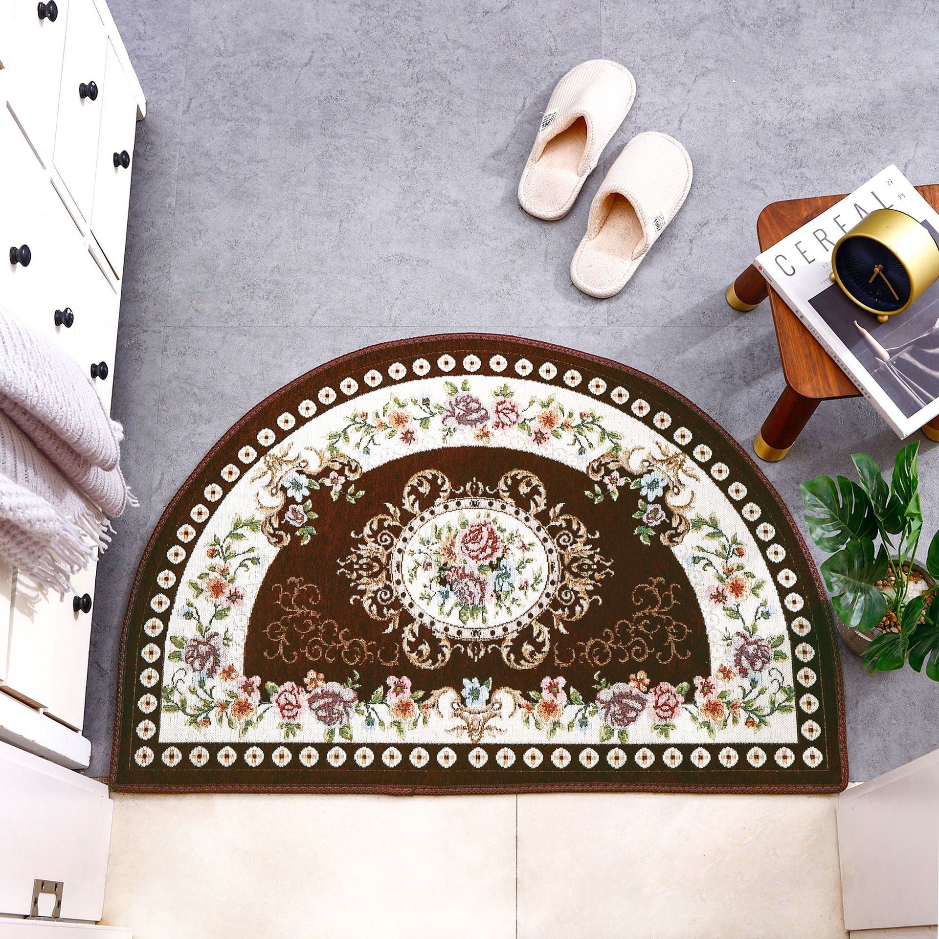 A European Style Semicircle Entrance Carpet with floral designs and a pastel color scheme on a wooden floor, next to a stool and a pair of slippers.