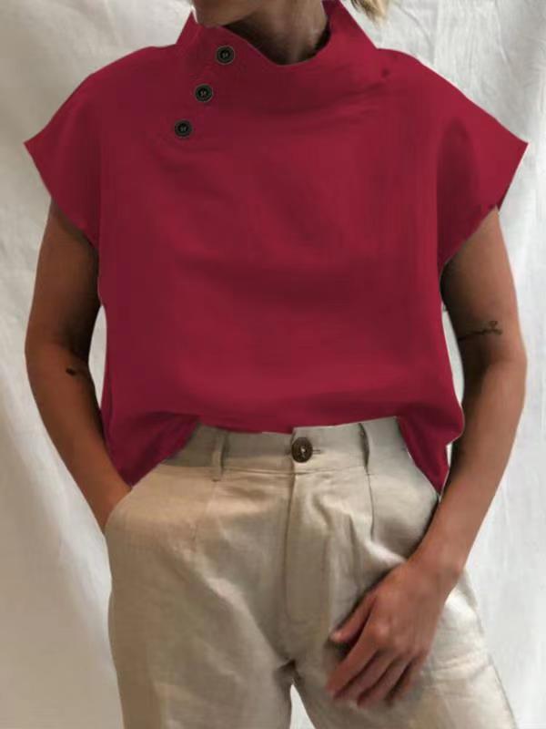 Person wearing a Stylish Blouses Summer Women Cotton Linen Short Sleeve Buttons Solid Shirt in navy blue, paired with light-colored trousers, standing against a plain backdrop.