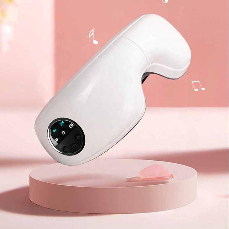 A woman wearing a 2023 New Bluetooth Eye Massager Foldable Smart Eye Massager Hot Compress Massage Eye Mask against a pink background. She is touching the device with one hand, eyes covered, conveying a sense of engagement or adjustment.