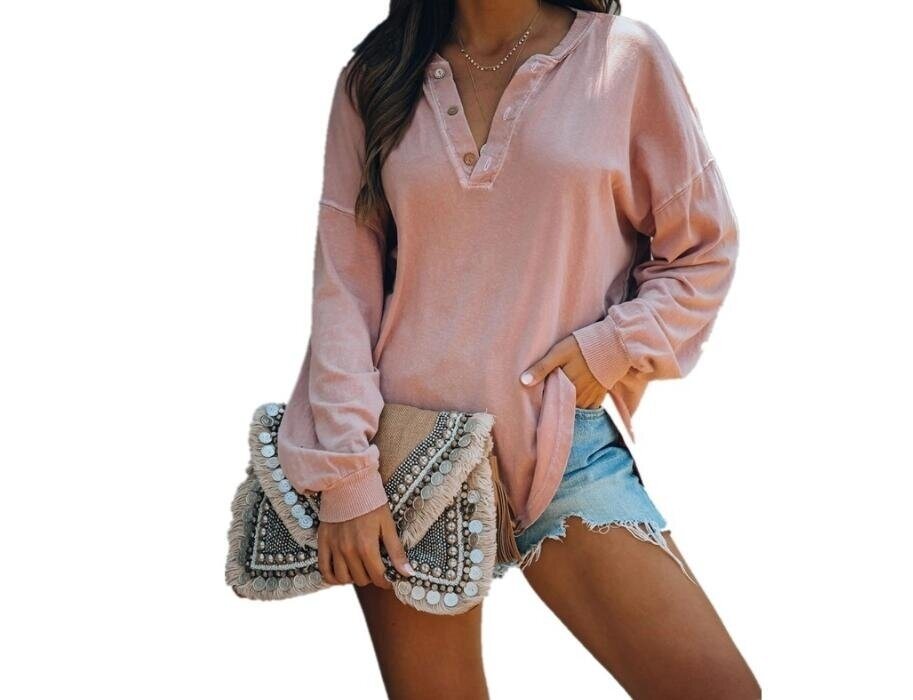 A woman wearing a pink V-neck buttons long sleeve shirt tunics top and denim shorts, holding a decorated clutch bag. Only her torso and thighs are visible.