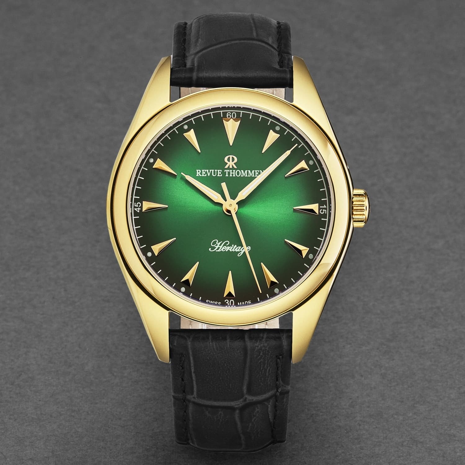 Revue Thommen Men's 'Heritage' Green Dial Black Leather Strap Automatic Watch 21010.2514 features a green dial, gold-toned case, and black leather strap. The dial displays gold hour markers and hands, with "Revue Thommen" and "Heritage" written on it.