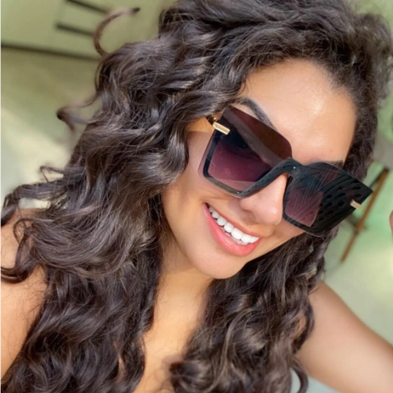 The Sunglasses Ocean Slices Multicolor Personality Trend Sunglasses for Men and Women feature a black oversized square design with gradient lenses, highlighted by thin gold accents on the temples and a small decorative logo near the hinges. These polarized sunglasses offer UV400 protection, making them both stylish and practical for fashion wear.