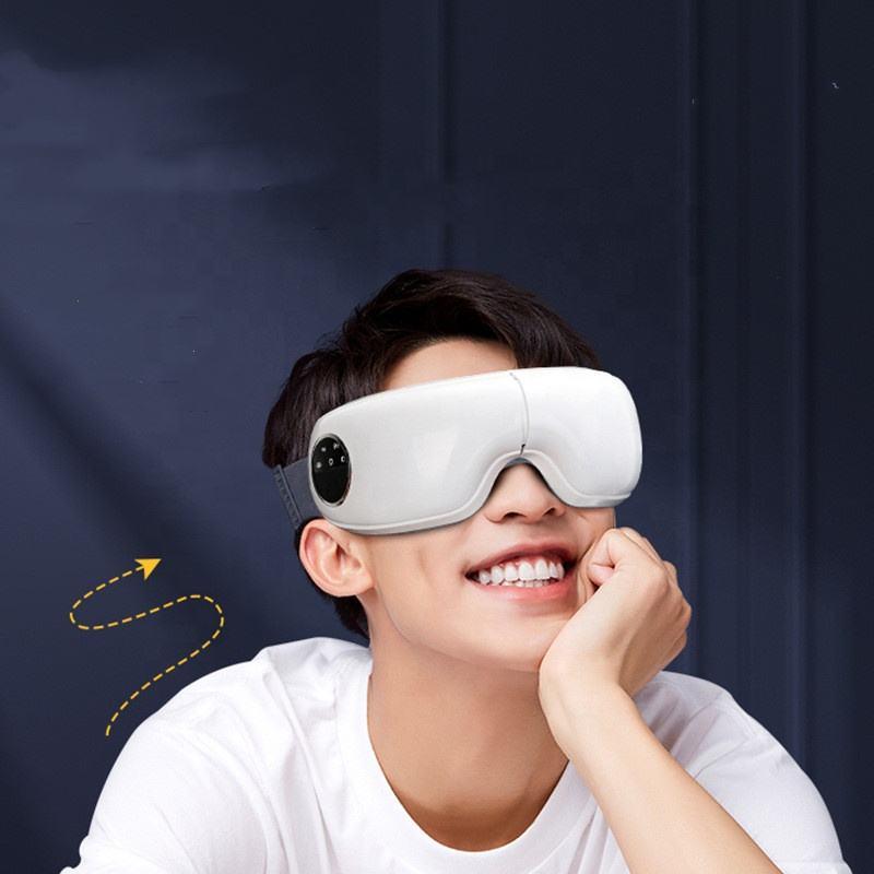 A woman wearing a 2023 New Bluetooth Eye Massager Foldable Smart Eye Massager Hot Compress Massage Eye Mask against a pink background. She is touching the device with one hand, eyes covered, conveying a sense of engagement or adjustment.